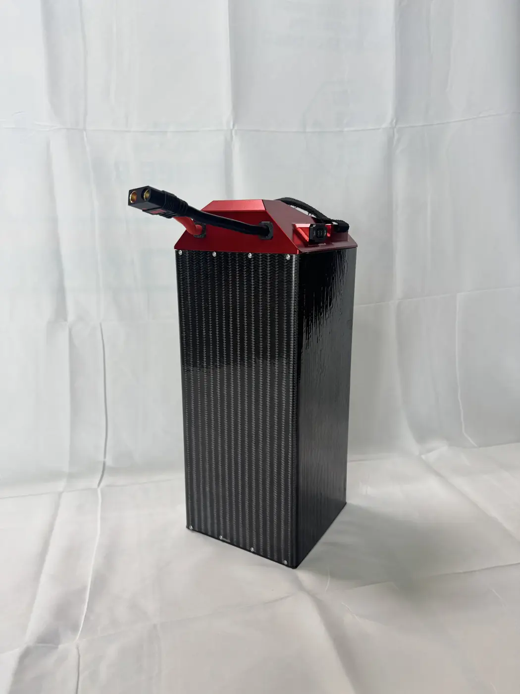 SPM LB 60/60 battery pack at an angle, showing the ribbed carbon fiber case and machined red cap
